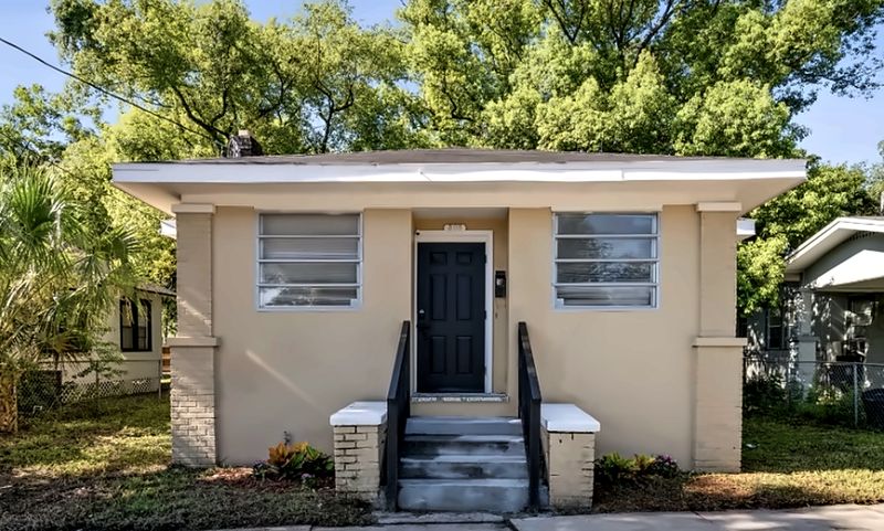 Front of the house: a stucco bungalow with a black front door